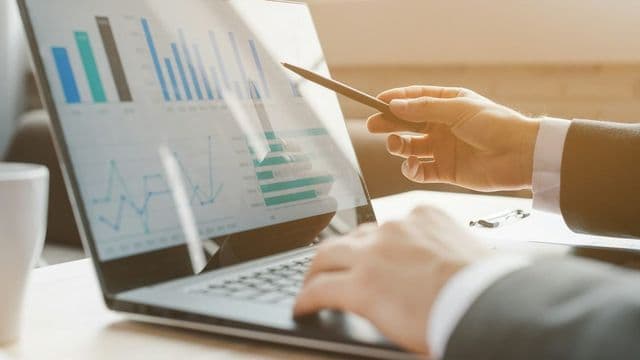 Profissional analisando gráficos financeiros em laptop, MBA em Gestão Financeira