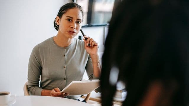 Psicóloga em consultório escutando atentamente um cliente durante sessão de terapia
