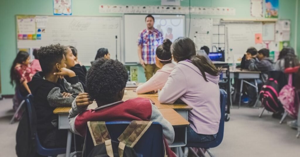 Professor conduz aula para turma diante do quadro em sala de aula de ensino fundamental