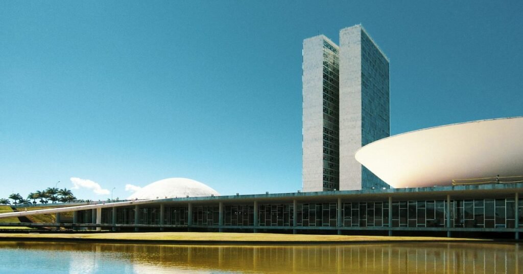 Congresso Nacional em Brasília com as duas torres e as cúpulas refletidas no espelho d'água em dia claro