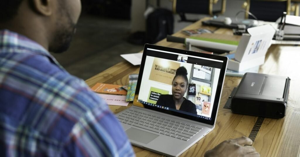 Estudante em videochamada com tutora EAD que conduz a aula na tela do notebook