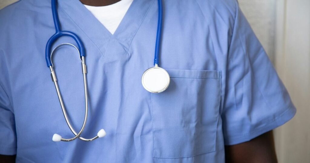 Enfermeiro de uniforme azul com estetoscópio ao pescoço, pronto para o atendimento em oncologia