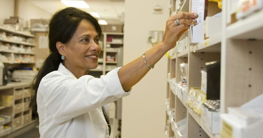 Farmacêutica organiza medicamentos em prateleira de farmácia hospitalar