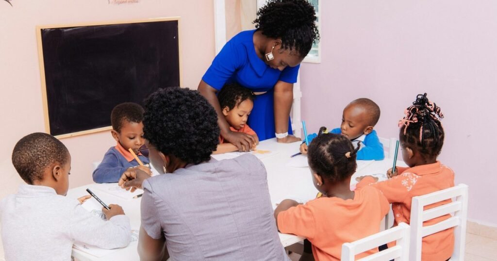 Professora orienta criancas em atividade de desenho em sala de educacao infantil colorida