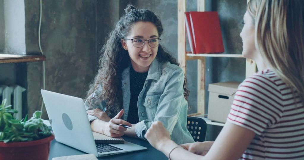 Duas profissionais conversando durante atendimento de orientação social, simbolizando o trabalho de direitos humanos e ressocialização