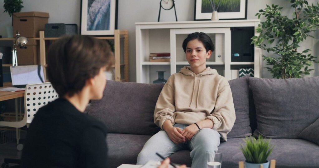 Psicólogo conversando com adolescente em sessão de psicoterapia em consultório