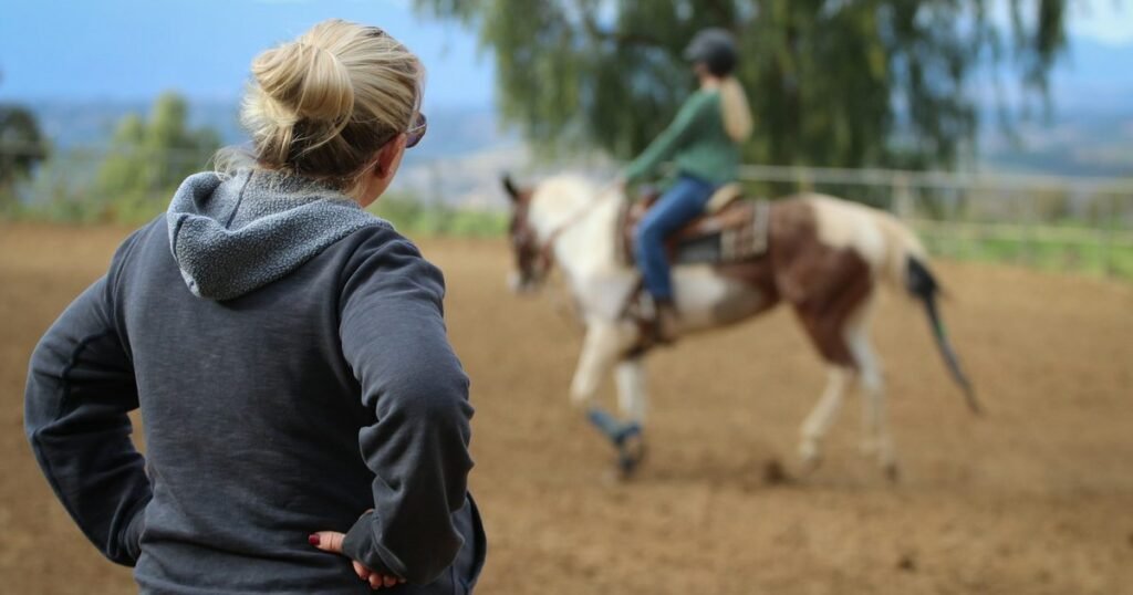 Instrutora acompanhando sessão de equoterapia com cavalo ao ar livre
