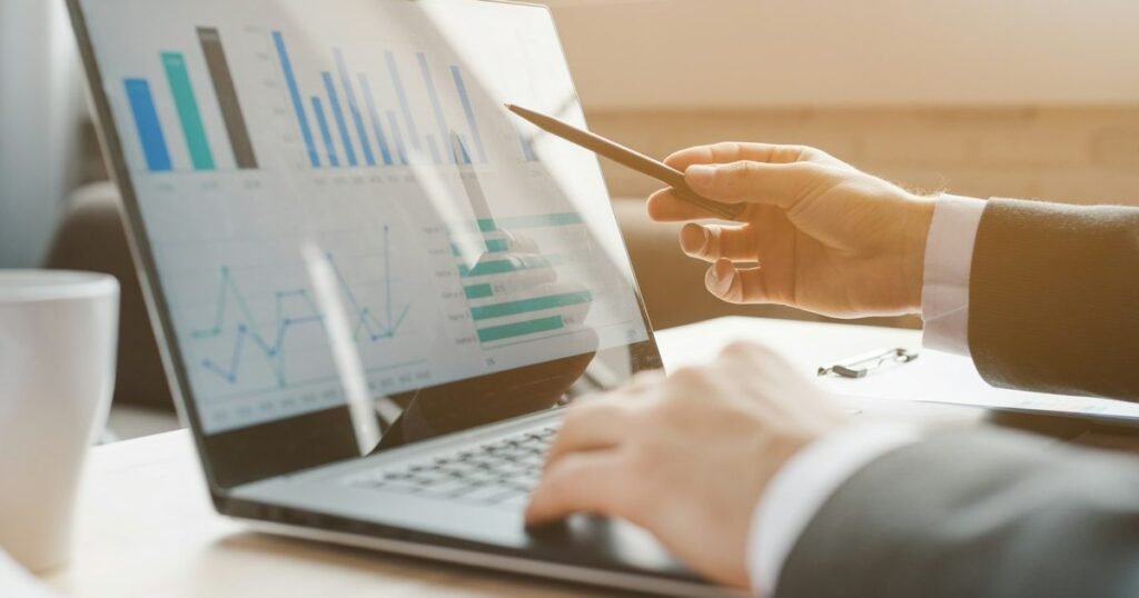Profissional analisando gráficos de desempenho em laptop, representando a gestão de riscos corporativos
